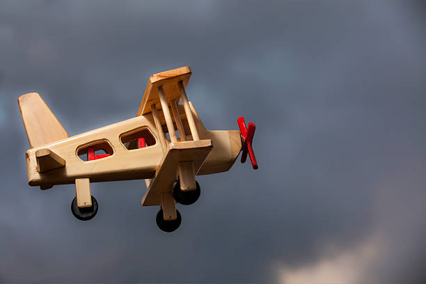 istock Wooden plane flying under the stormy sky - Side view 525028436