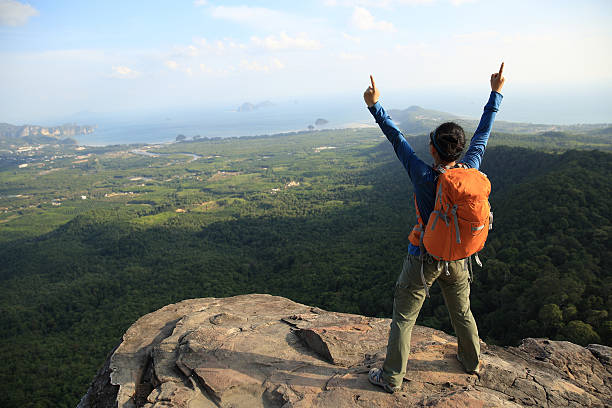 istock cheering successful woman hiker open arms at mountain peak 525029316