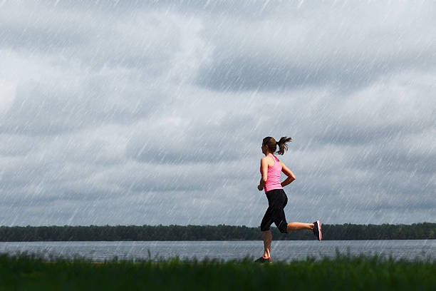 jeune femme sportive jogging sur un jour de pluie - courir sous la pluie photos et images de collection