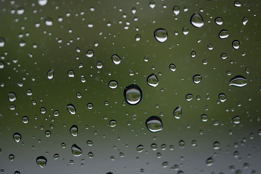 A macro photo of raindrops on a window near nature.