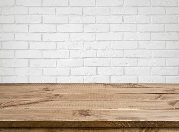 Rough wooden texture table over defocused white brick wall background