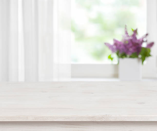 istock Wooden table on defocused window with purple flower pot background 525034358