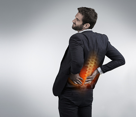 Shot of a businessman holding his injured back that's highlighted in red