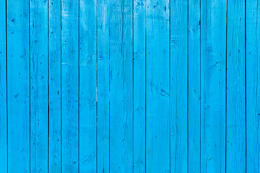 Vibrant striking blue coloured wooden background of wooden planks painted with a rustic coloured aqua wood paint.