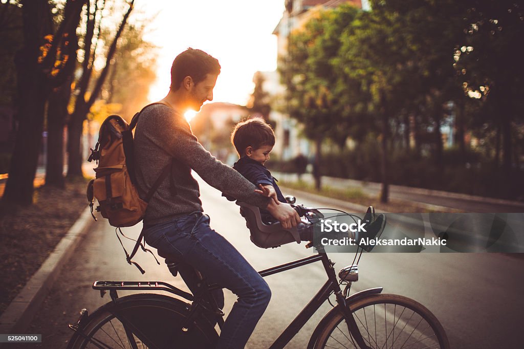 Fun and games on a bicycle Father and his son cycling together outdoors on a beautiful sunny day  City Stock Photo