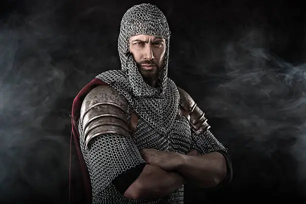 Portrait of Medieval Dirty Face Warrior with chain mail armour. Smoke Cloud on Dark Background