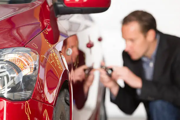 Photo of Adult appraiser looking at car, estimate for fix