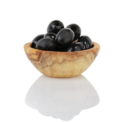 black olives from can in wood bowl, isolated on white