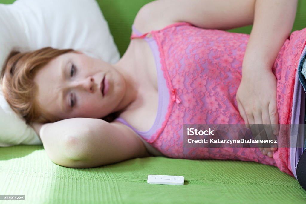 Positive result of pregnancy test Teenager lying on bed with positive result of pragnancy test Adolescence Stock Photo