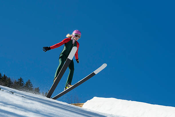jovem mulher de salto de esqui desembarque contra o céu azul - ski jumping hill imagens e fotografias de stock