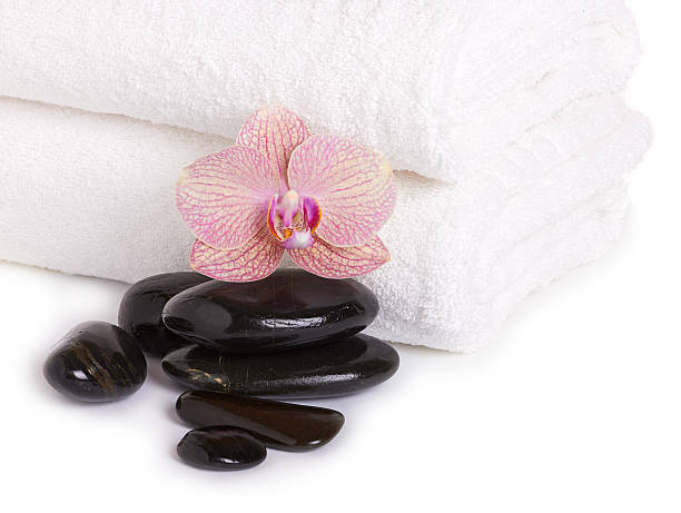 istock pink orchid and spa stones on white towel 525044677