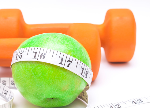 Green apple and a dumbbell on white background