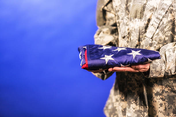 istock Military Soldier Presenting USA Flag Folded 525061361