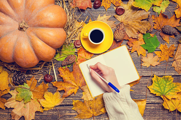 istock Female hand wrinig something in notebook on autumn background. 525063399