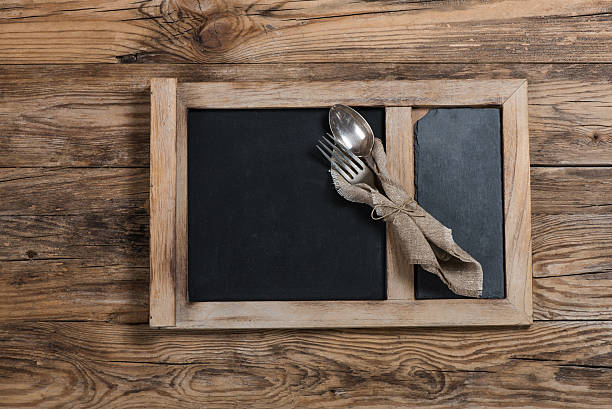 istock Dinnerware  fork and spoon in napkin on chalkboard on wooden 525071809