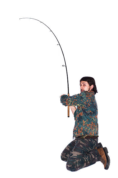 A man with a fishing rod in a photo studio, standing in his knees. White background.