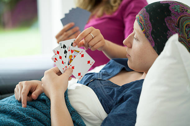 Cancer girl playing cards Cancer girl playing cards in hospital bed hospital card stock pictures, royalty-free photos & images