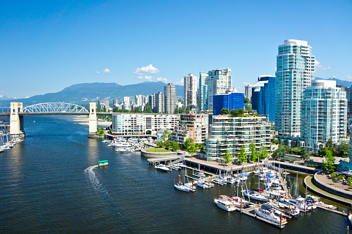 Scenic view of a quay and dock with boats sailing in a harbor in the city on a summer afternoon