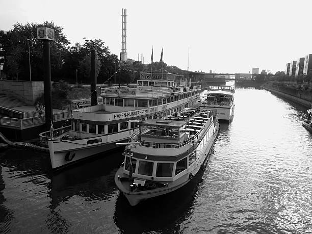 Cruise vessels moored on the Innenhafen (Inner Harbour) in Duisburg, Germany. Once, during the Industrial Revolution was the central harbour and trading point of the town. It is has now been transformed into a modern district combining employment, housing, culture and on water leisure activities. In the background is the Schwanentorbrücke, a historical moving bridge