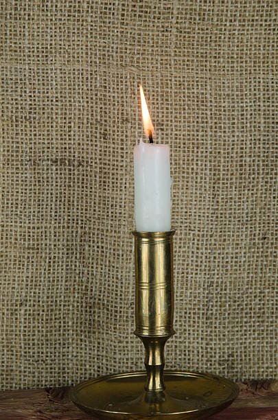istock Single candle in candlestick at burlap background 525111129
