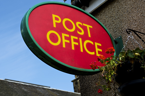 Red post office sign oval in the wall outside