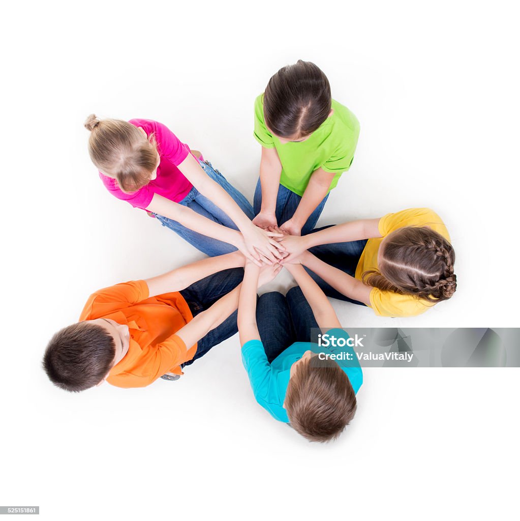 Group of children sitting on the floor. Group of smiling children sitting on the floor in a circle holding hands - isolated on white. Child Stock Photo