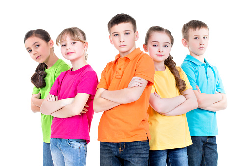 Group of children with crossed arms in colorful t-shirts standing together on white background.