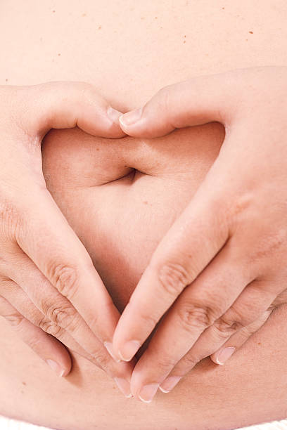 istock Pregnant Belly with fingers Heart symbol 525175721