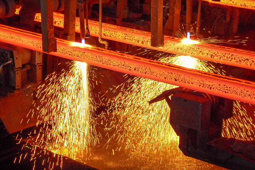 Red hot steel billets with sparks on a continuous casting machine at torch cutting in a steel plant production site