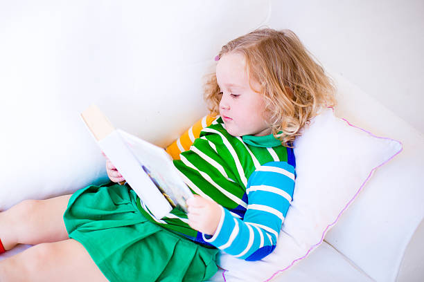 istock Little girl reading a book 525179193