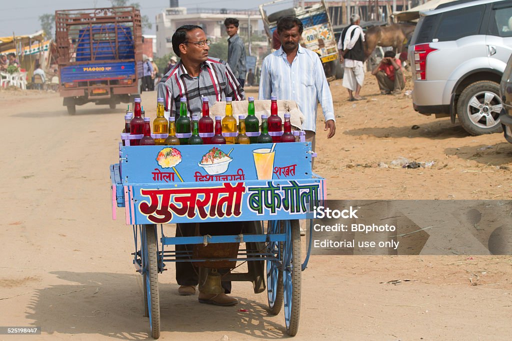 snack vendor at Pushkar Pushkar, India - November 11, 2013.  Indian man pushing his shaved ice cart at the fair.  The Pushkar fair is an annual five-day event and one of the world's largest camel fairs, with over 50,000 camels brought in from around the region. Apart from the buying and selling of livestock, Pushkar lake is an important Hindu pilgrimage spot with thousands of Hindus coming to take a dip in the and pray to the deities. Cart Stock Photo