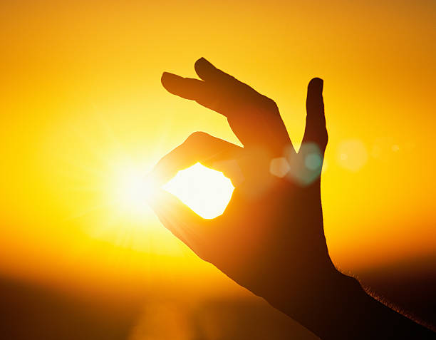 istock Silhouetted hand makes OK sign around the setting sun 525205712
