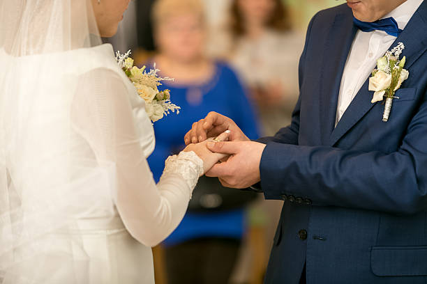 Groom puts ring on brides finger in church.