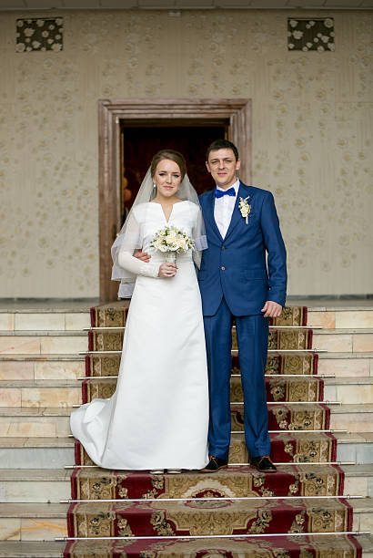 istock Happy newly married couple posing on stairs at hall 525205852