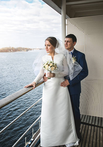 istock Smiling newly married couple looking at river from hotel room 525206188