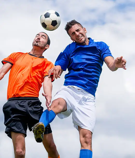 Men playing soccer and going for the ball