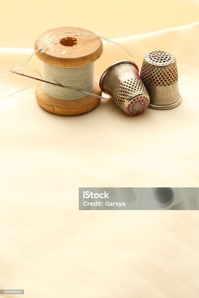 Sewing thimbles, bobbin and needle Sewing thimbles, bobbin and needle on silk cloth Art And Craft Stock Photo