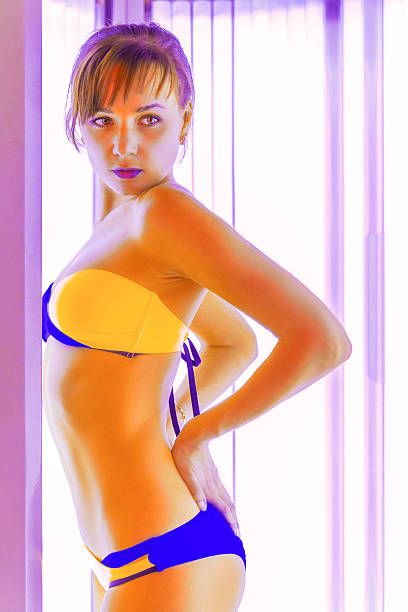 istock Slim young woman standing in solarium getting sun tan 525209644