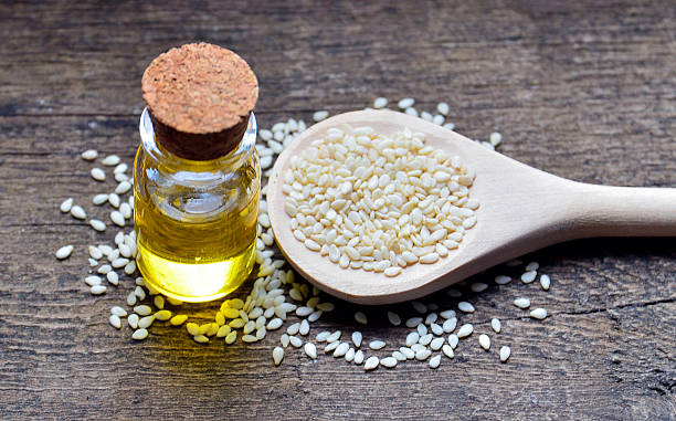 Sesame seeds on wooden spoon and sesame oil. stock photo