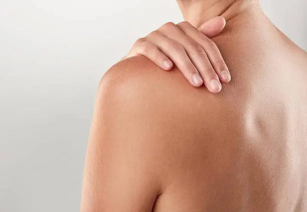 Closeup studio shot of a woman touching her bare shoulder