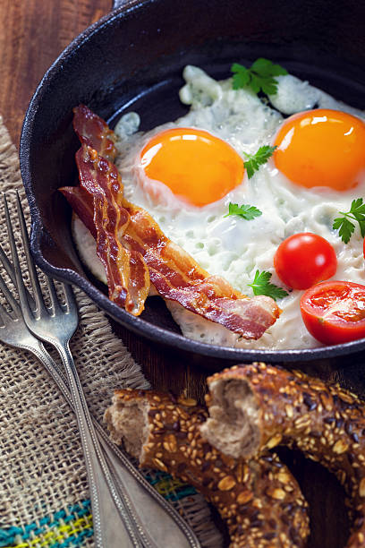 istock Pan of fried eggs, bacon and cherry tomatoes with bread 525214302