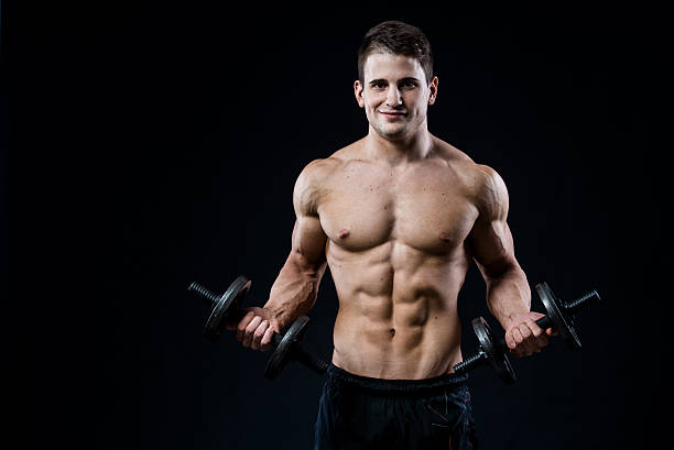 istock Handsome power athletic man training pumping up muscles with dumbbells 525215218