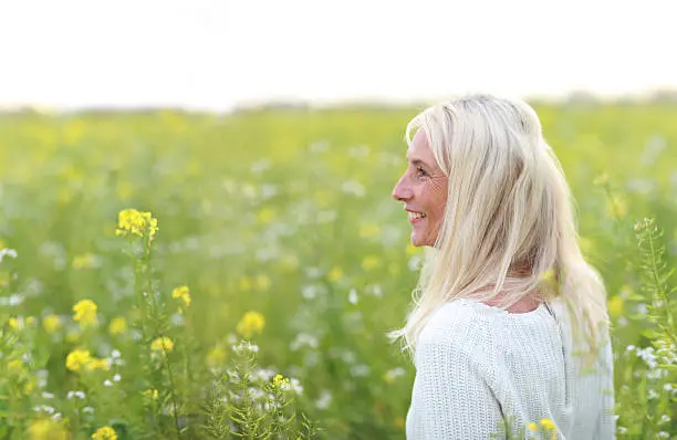Happy matured woman with scarf smiling in beautiful flowerfield