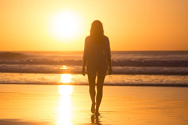 istock Lady walking on sandy beach in sunset. 525216838