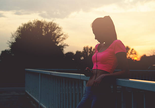 Fit young woman relaxing after exercise on the bridge, healthy lifestyle