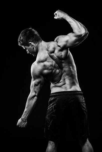 istock Young and fit bodybuilder athlete demonstrates biceps back view isolated 525218086