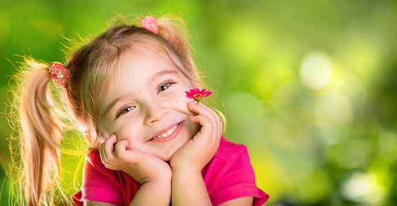 Cute Child With Purple Daisy In Spring Garden