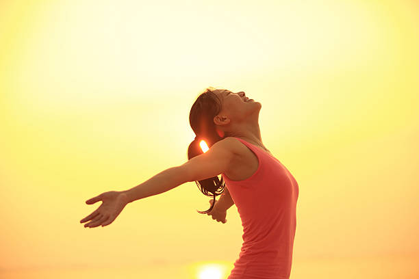 istock cheering woman open arms to sunrise at seaside 525218933