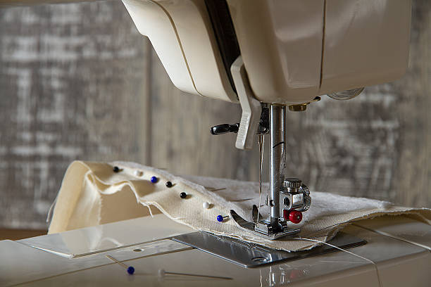 istock Sewing machine foot with fabric in front of wood wall 525223264
