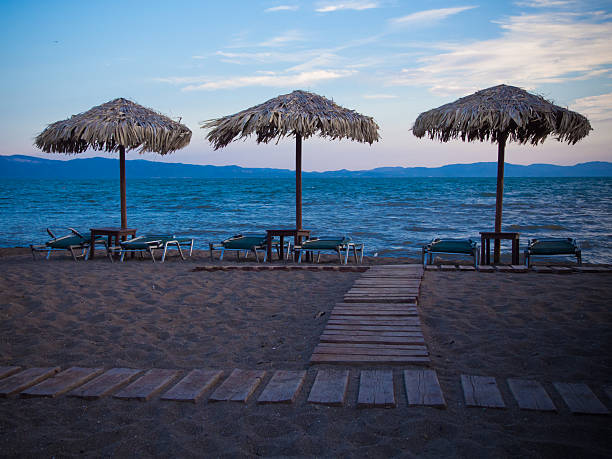 Three beach umbrellas on a beach in Skala Kallonis on Lesbos in Greece in evening light